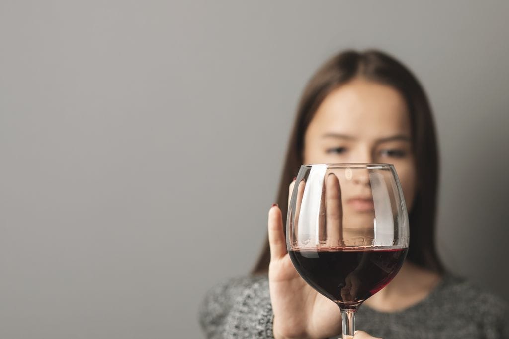 Adolescente rechazando una copa de vino