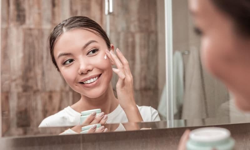 mujer aplicando crema en su rostro