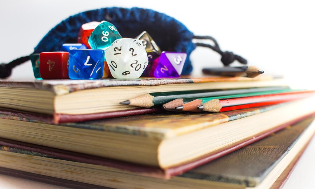 close up of dice and pencils on top of books