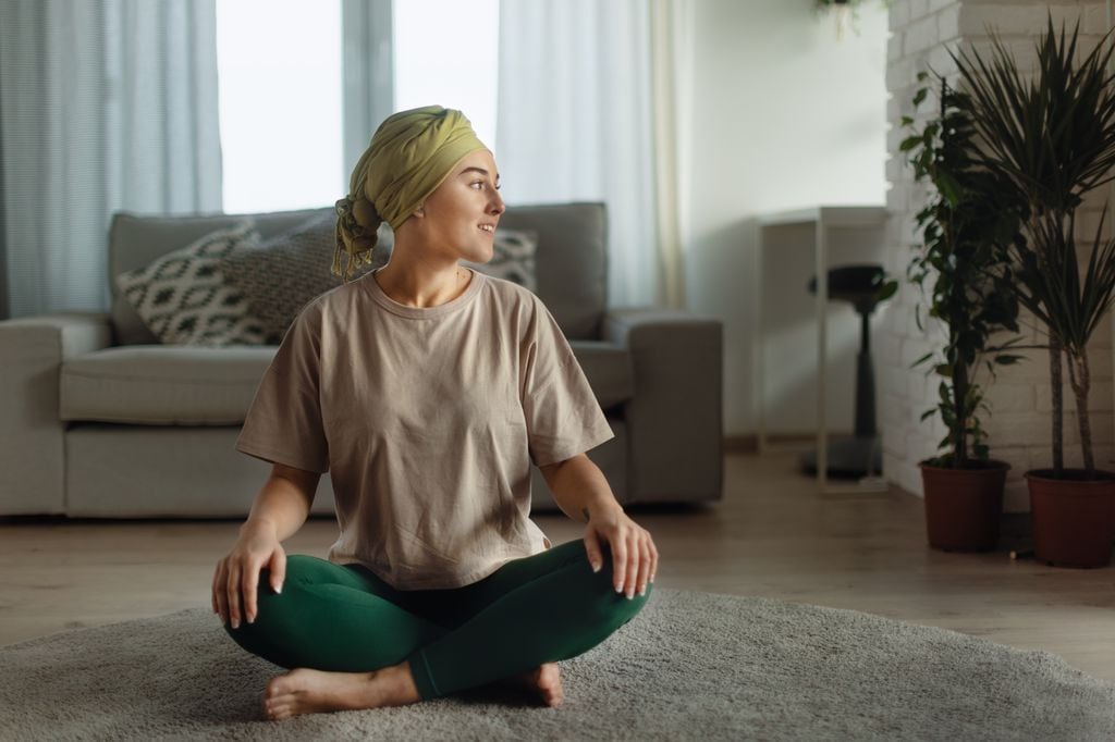 mujer con cáncer sentada en la alfombra, preparada para hacer yoga