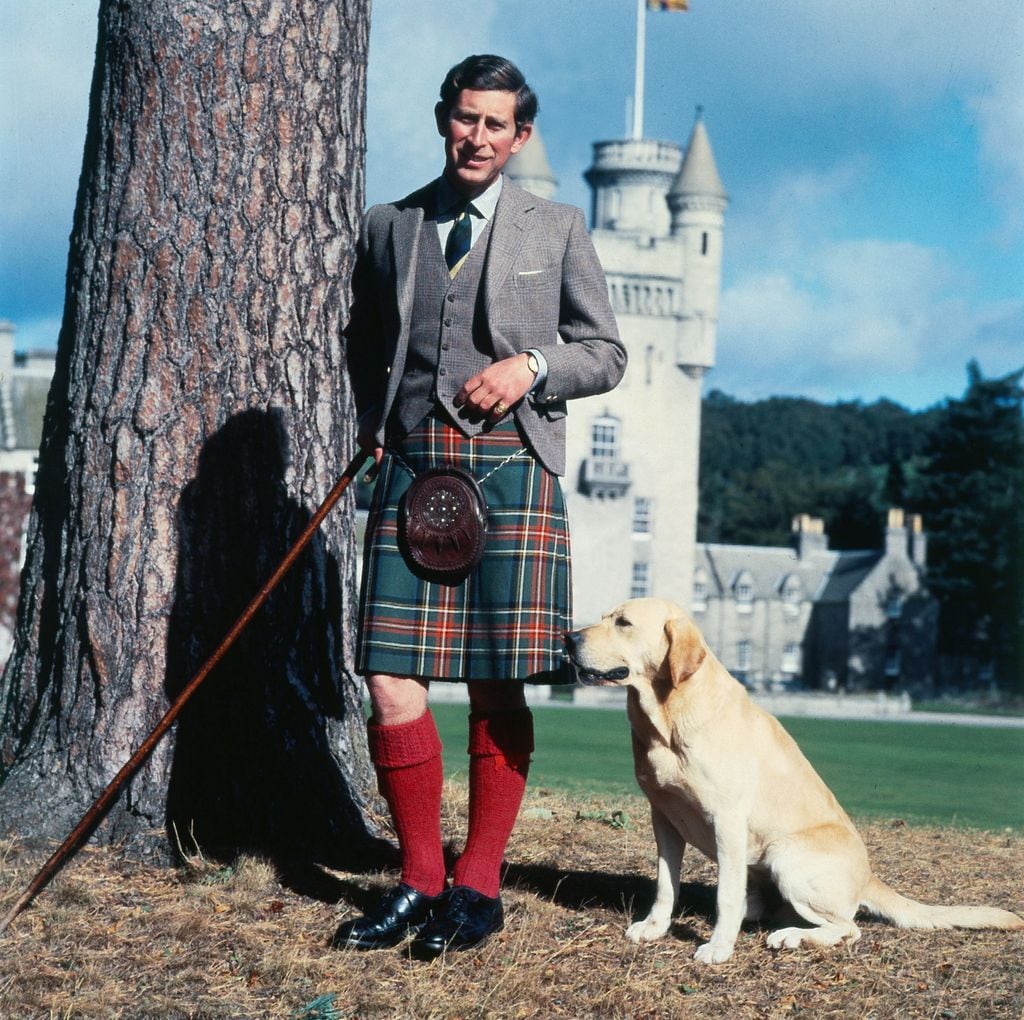 Carlos III, con falda escocesa y uno de sus perros en los terrenos del castillo de Balmoral en 1978