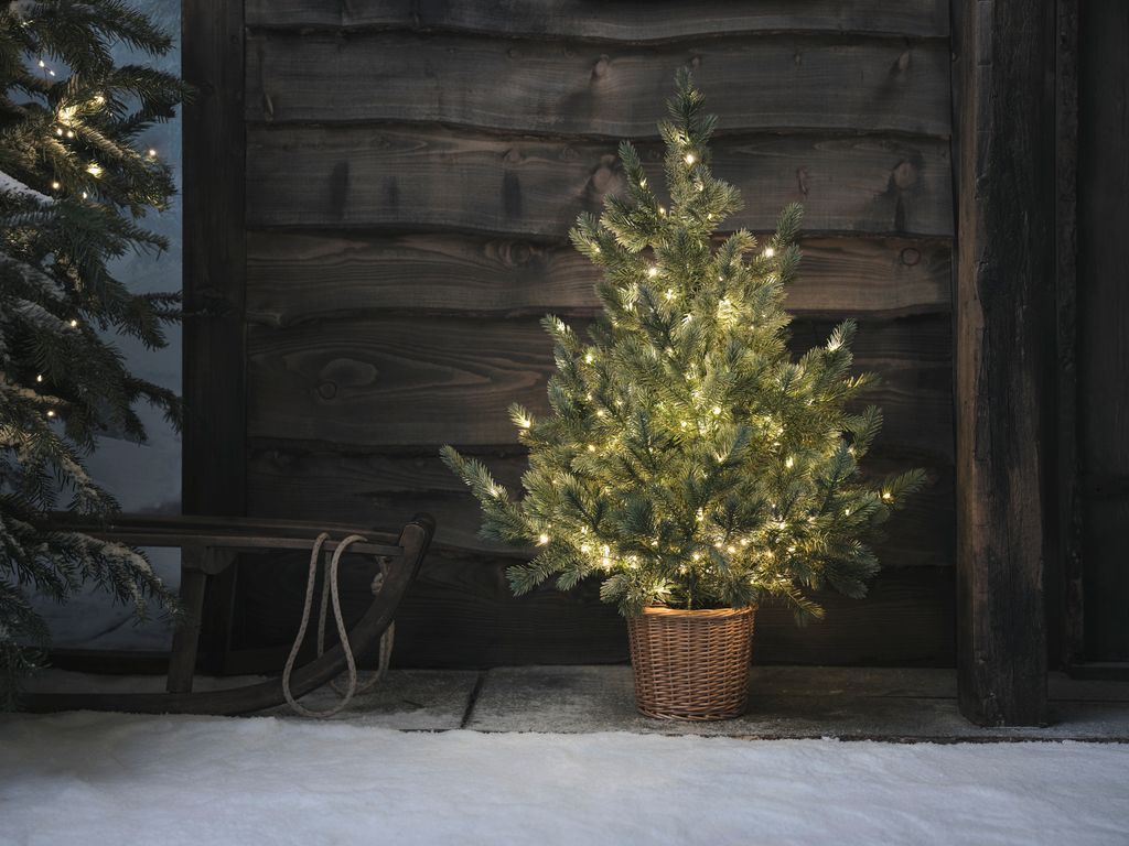 Árbol de Navidad con guirnalda de luces en exterior casa nevada 