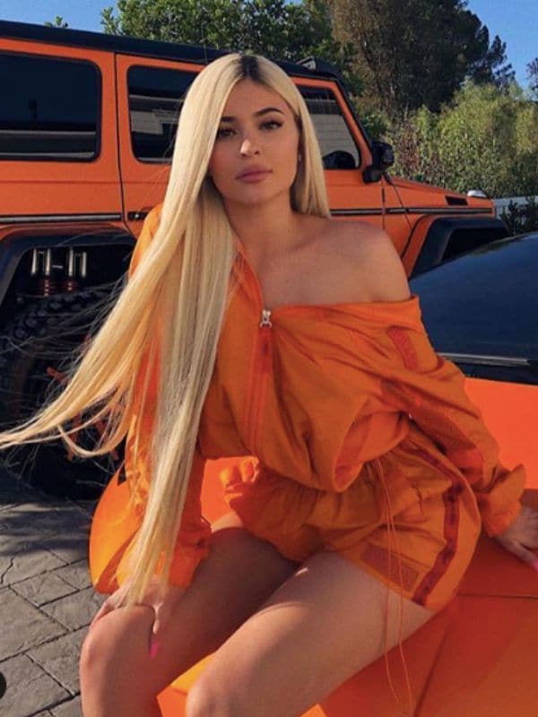 Kylie Jenner rubia con extensiones largas y conjunto naranja 