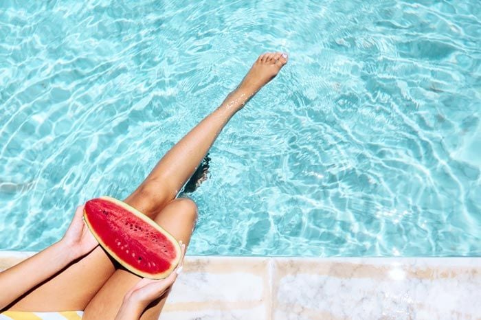 mujer en la piscina con un trozo de sandía