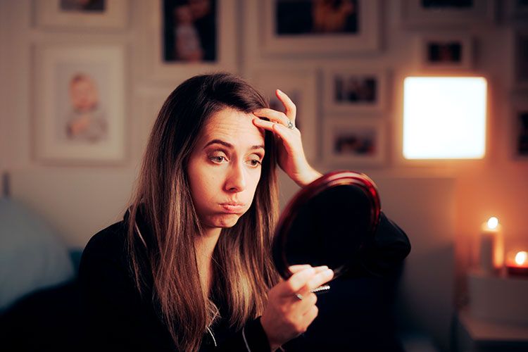 Mujer mirándose al espejo viéndose las arrugas de la edad