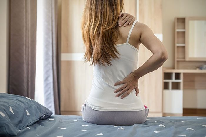 mujer en la cama con dolor de espalda