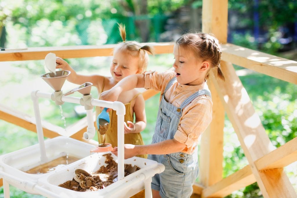 Niños jugando con juego de agua Montessori