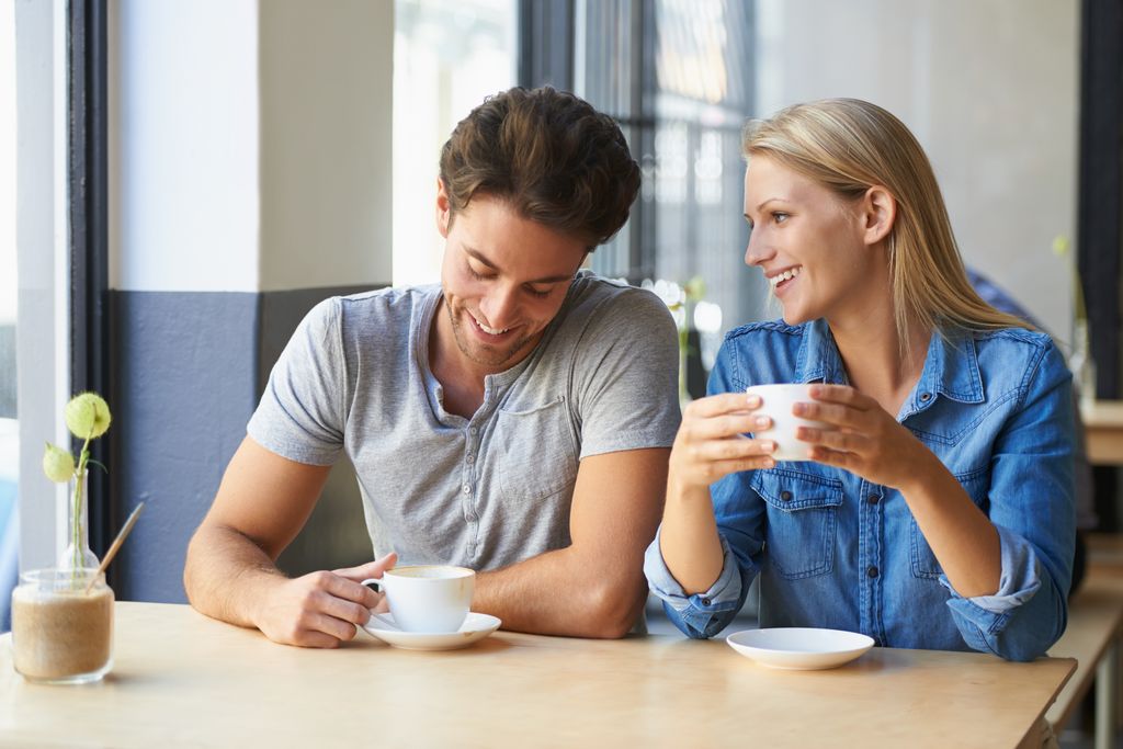 pareja sonriente tomando un café en una cafetería