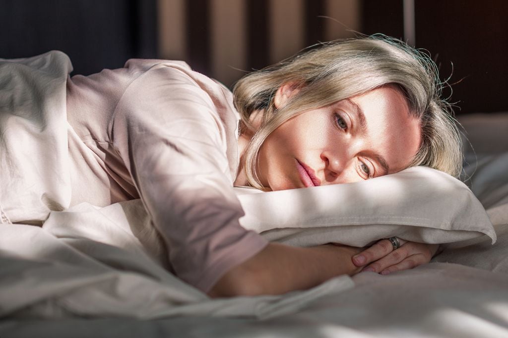 mujer tumbada en la cama, triste y cansada