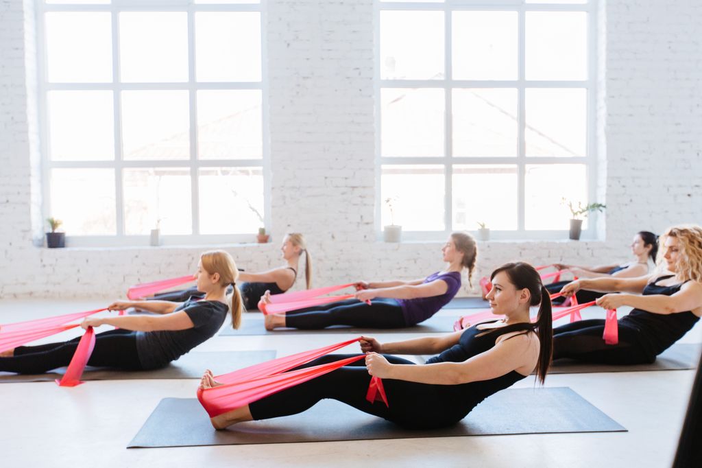 Grupo de gente haciendo Pilates con bandas