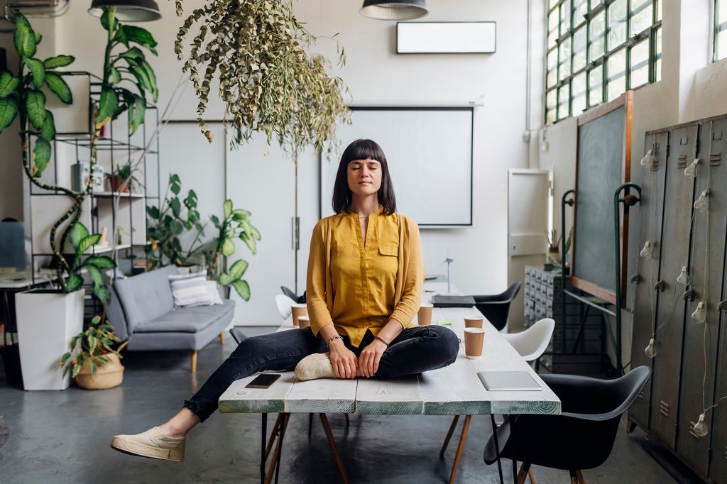 mujer meditando en una sala de reuniones de su oficina