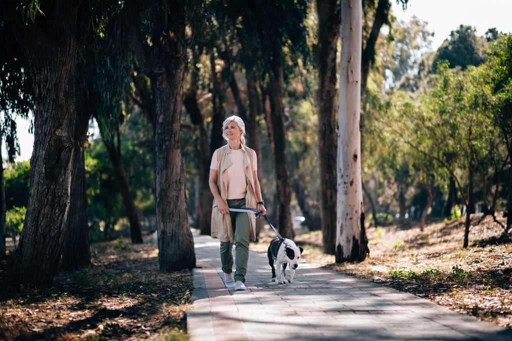 mujer madura caminando con un perro en el parque