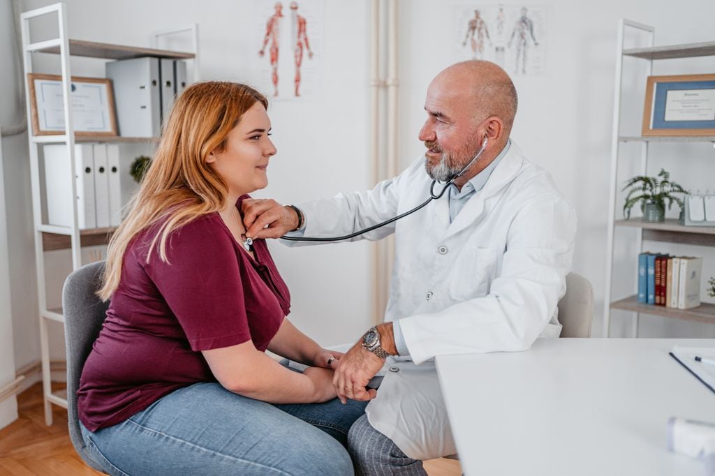 doctor auscultando a una paciente con sobrepeso en la consulta