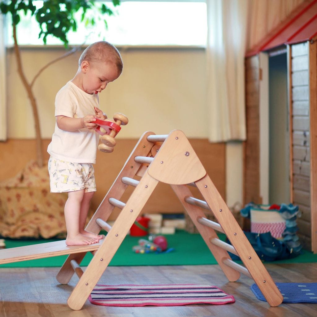 Niño jugando en triángulo Pikler