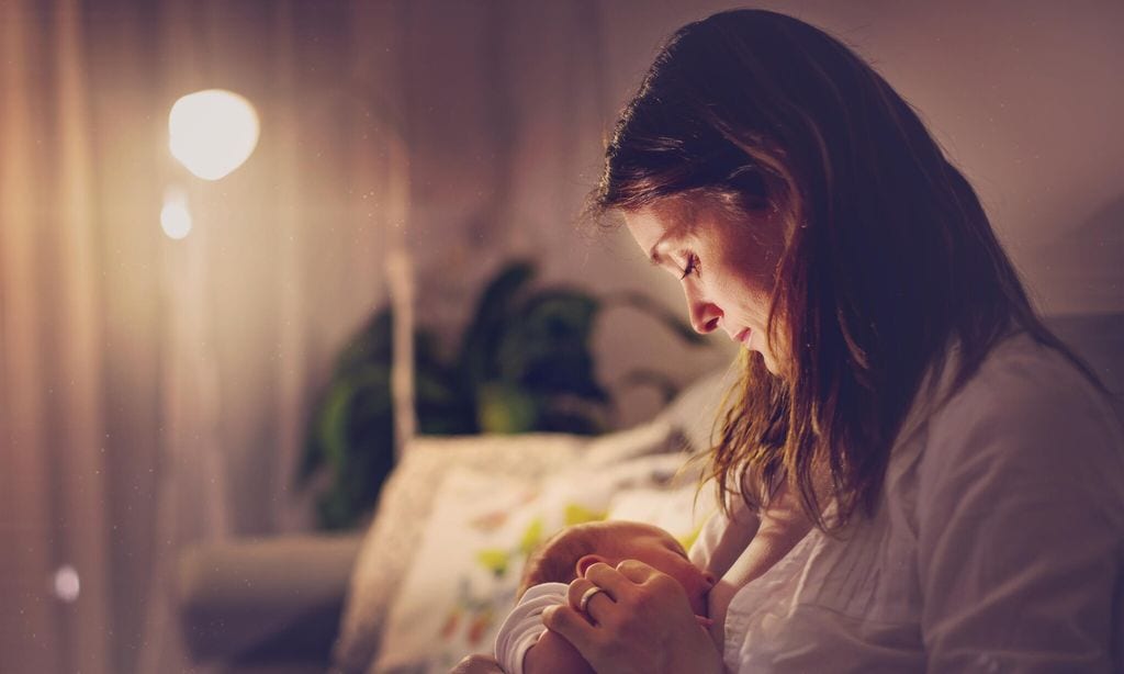 madre dando el pecho a su beb por la noche en su casa