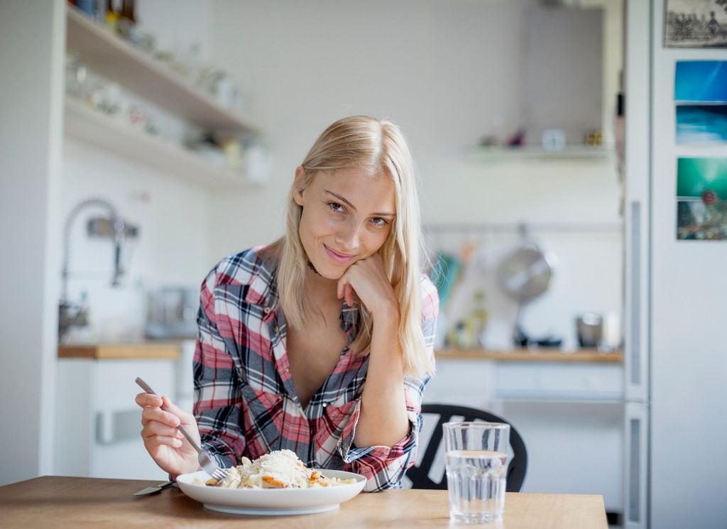 Mujer comiendo en la cocina