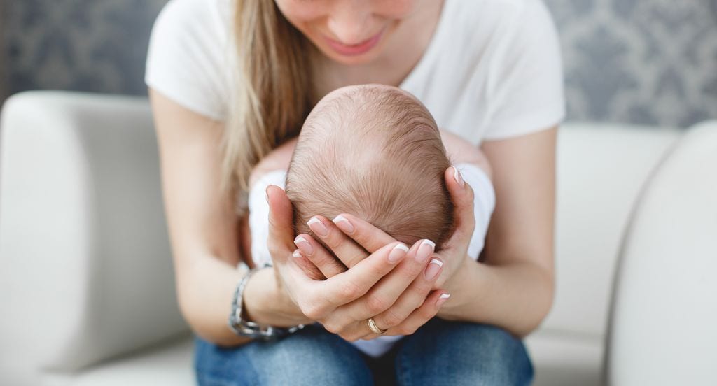 Mujer sosteniendo por la cabeza a su bebé