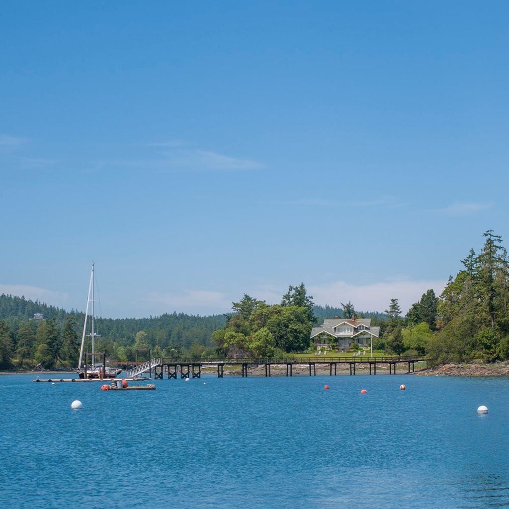 A sailboat docked at a house in a bay at Deer Harbor on Orcas Island in the San Juan Islands in Washington State, United States.