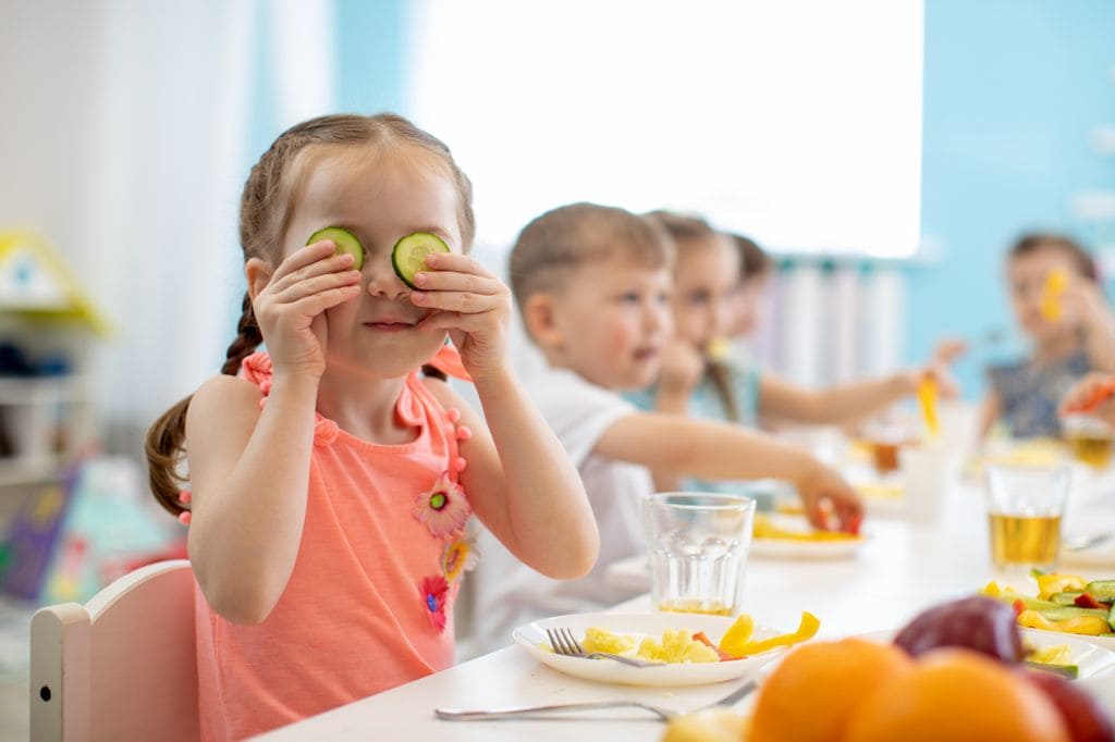 Niña comiendo en el colegio con unos pepinos en la cara