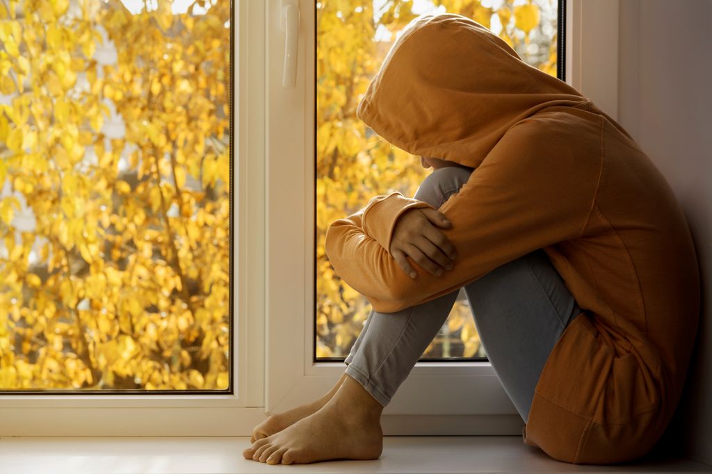 Adolescente con capucha en una ventana