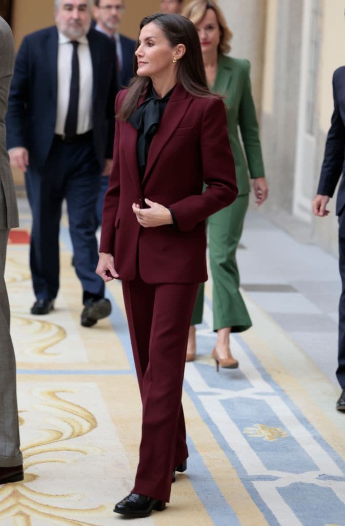 La reina Letizia con un traje burdeos y blusa de lazo