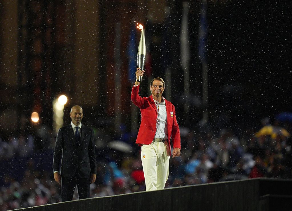 PARIS, FRANCE - JULY 26: Former French football player Zinedine Zidane (L) hands over the Olympic flame to Spanish tennis player Rafael Nadal at the Trocadero Stadium during the opening ceremony of the Paris 2024 Olympic Games in Paris, France, July 26, 2024. (Photo by Xu Chang - Pool/Getty Images)