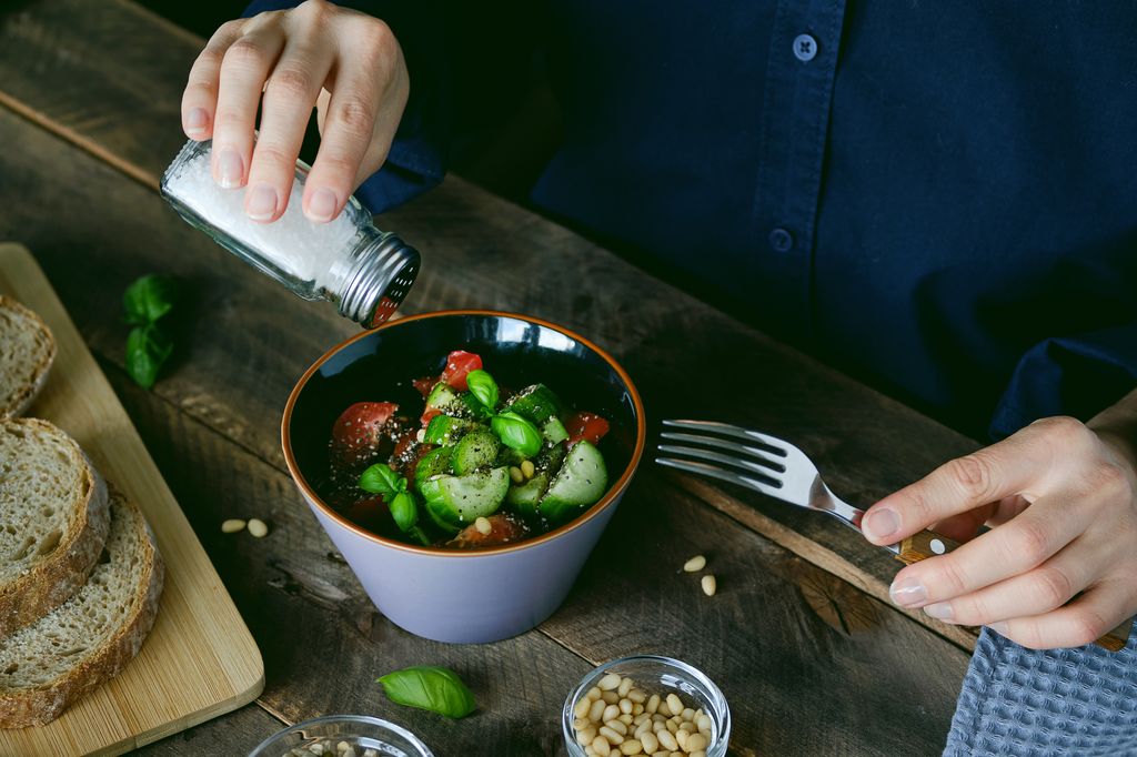 mujer aliñando su ensalada con sal