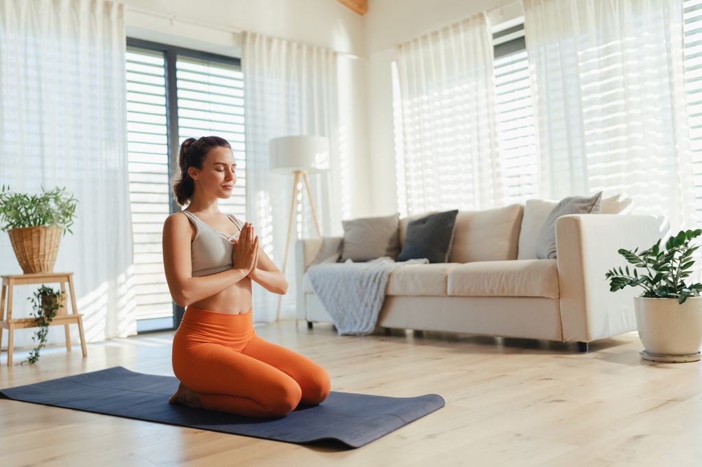 mujer joven haciendo yoga en casa