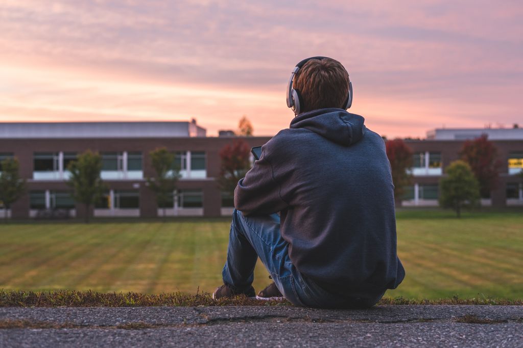 Adolescente solo en un atardecer con cascos puestos