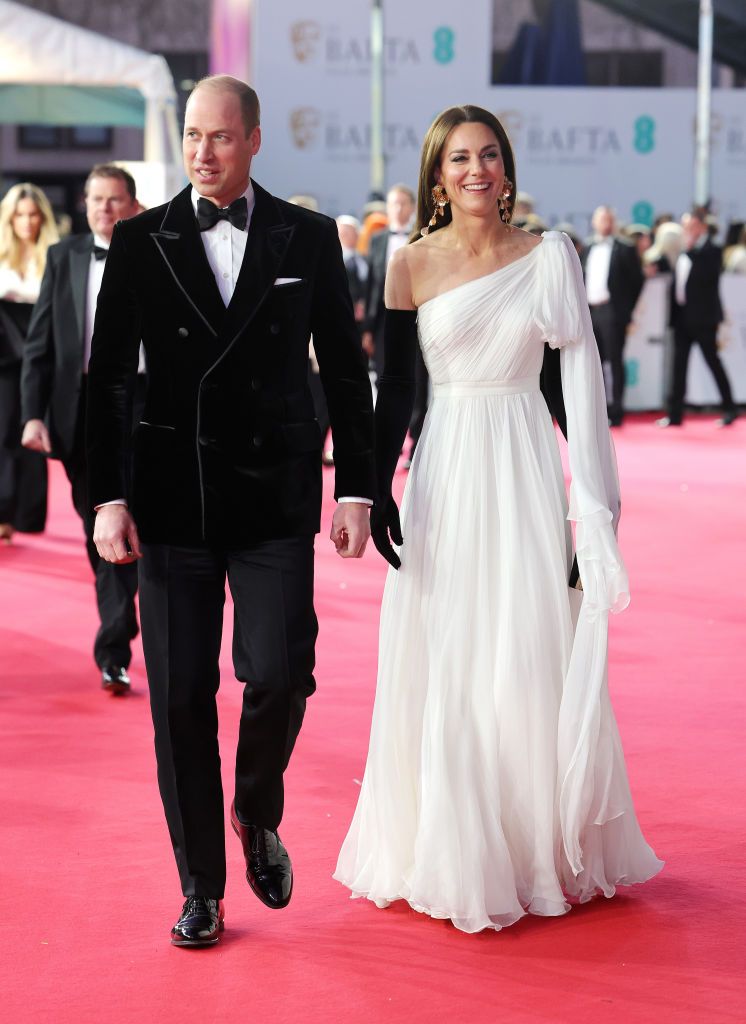 El Príncipe William y la Princesa Kate en los BAFTA 2023, Kate con un vestido blanco de Alexander McQueen y guantes negros, William con esmoquin negro de terciopelo.