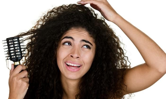 Joven peinando su pelo rizado rebelde