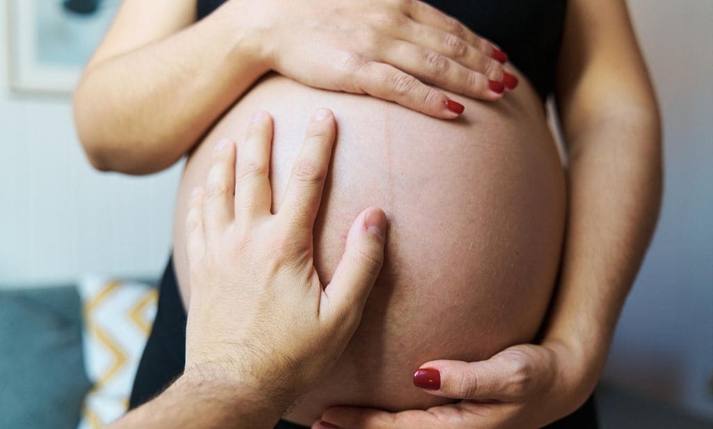 Hombre pone la mano en la tripa de su pareja