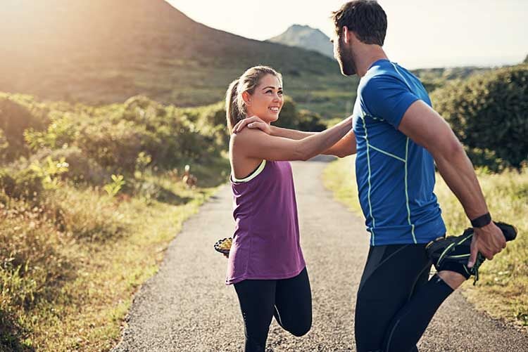 Una pareja estirando los músculos tras hacer ejercicio