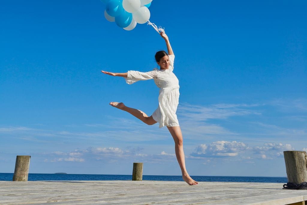 mujer feliz saltando con globos en la mano