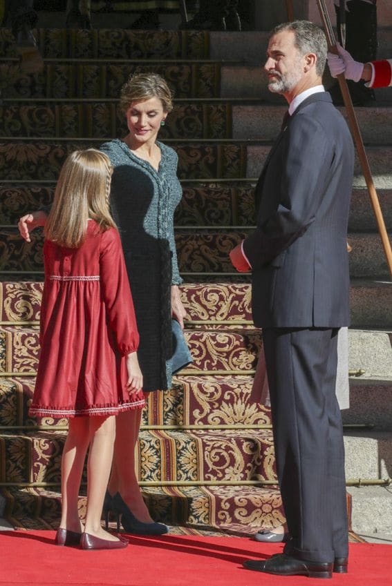 Doña Letizia, muy atenta con la Princesa de Asturias, ha lucido un favorecedor vestido abrigo en tweed y crepé de lana verde cromo con galón trenzado y cremallera meta de Felipe Varela, que ya llevó en 2014, durante el desfile militar del 12 de octubre
