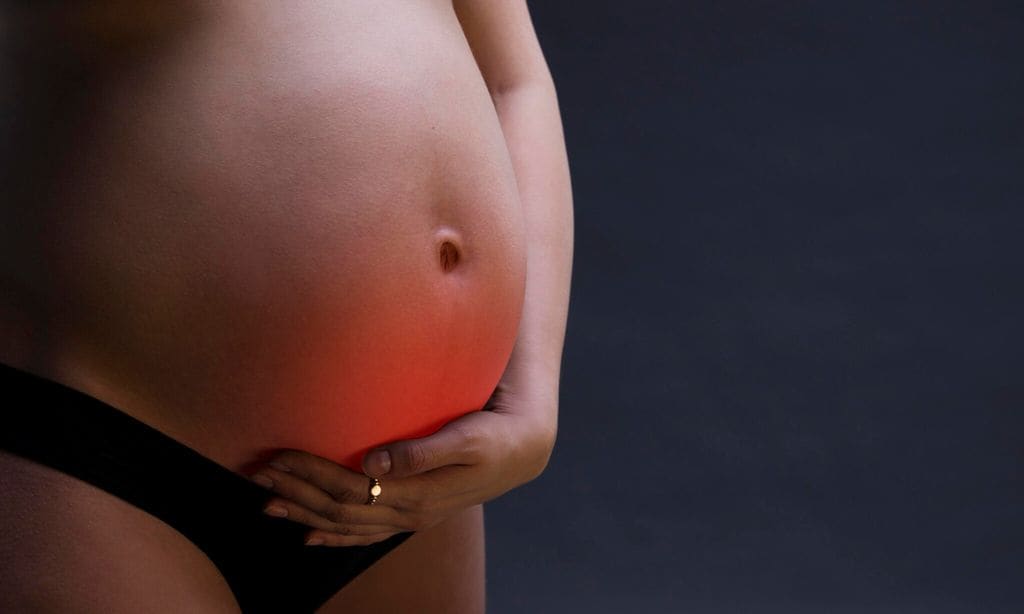 Caucasian pregnant woman in black lingerie with abdominal pain