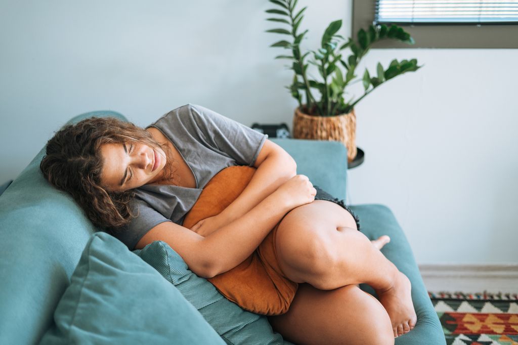 mujer deprimida abrazando un cojín en el sofá