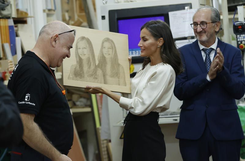 La Reina con una talla en madera de sus hijas