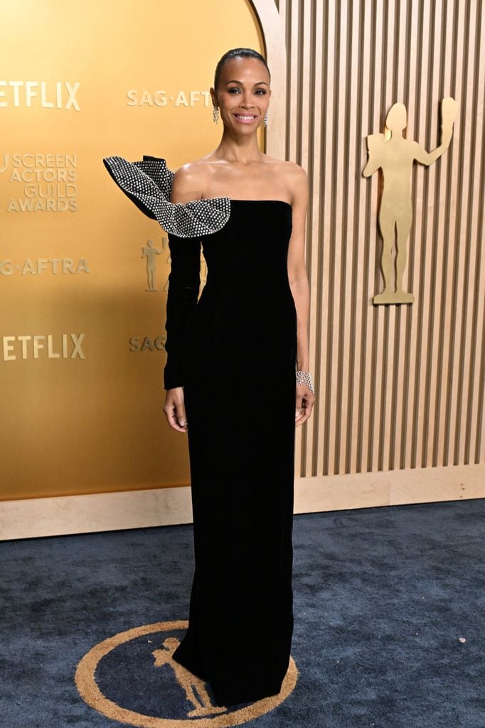 Zoe Saldaña con un vestido negro de Saint Laurent con manga asimétrica y detalle en el hombro, combinado con joyas de Cartier en los SAG Awards 2025.        