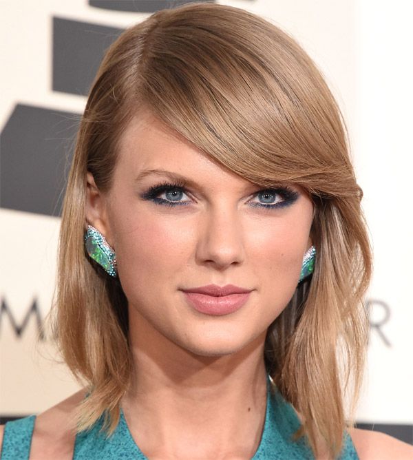 Taylor Swift, con un total look turquesa tanto su vestido como sus pendientes y maquillaje
