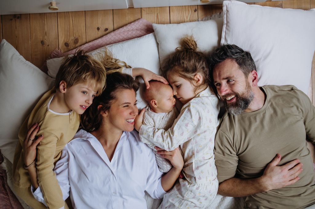 Familia con tres hijos tumbados juntos en la cama