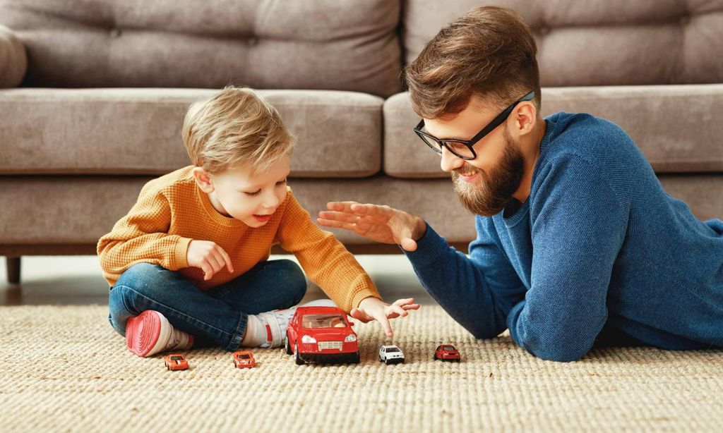 pap jugando con su hijo a los coches tumbados en el suelo