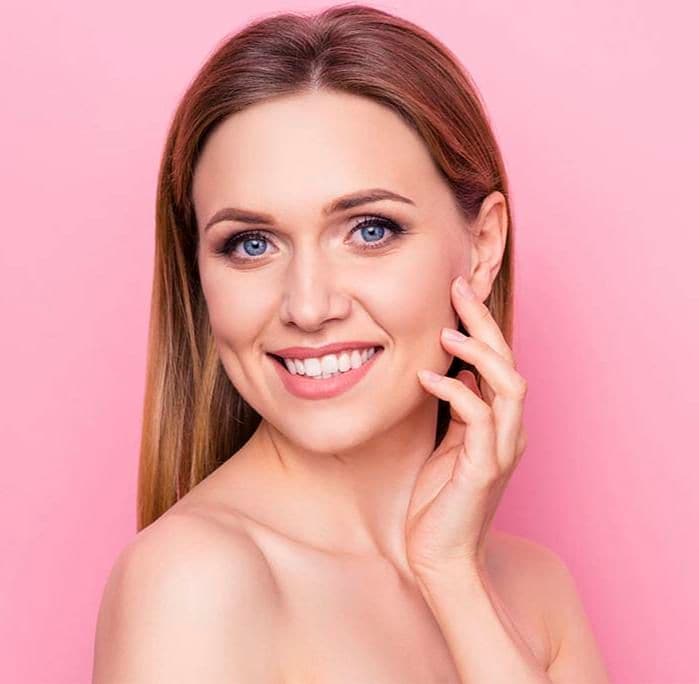 mujer rubia sonriente con mano sobre la mejilla