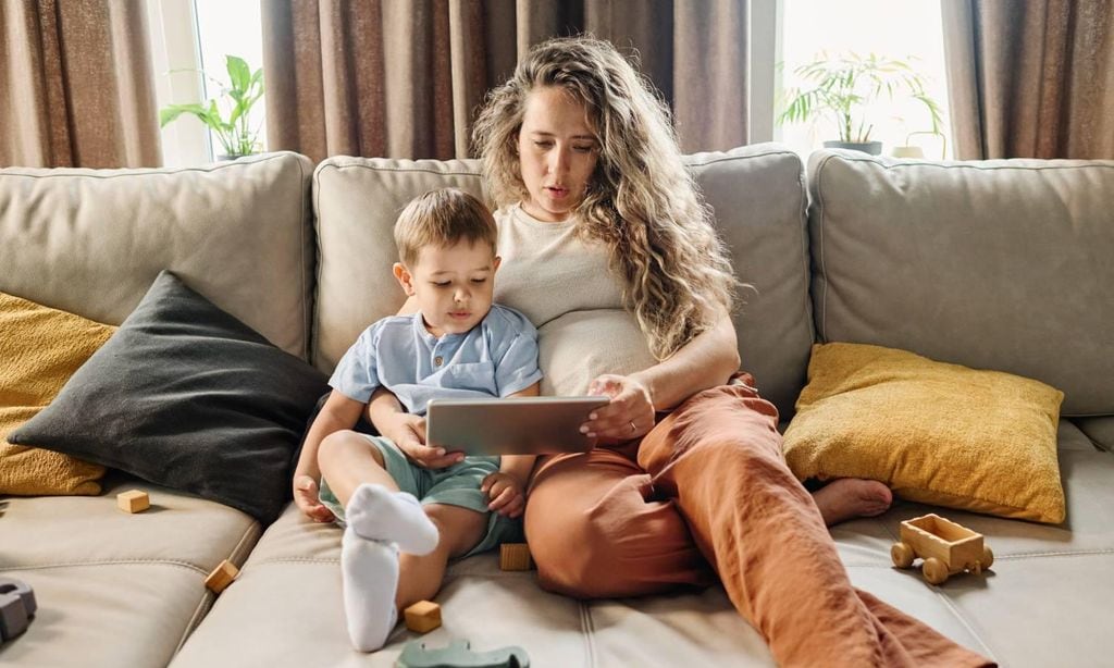 mam embarazada con su hijo mayor sentada en el sof viendo la tablet