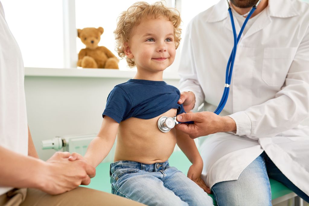 Niño en consulta mientras es auscultado por el pediatra