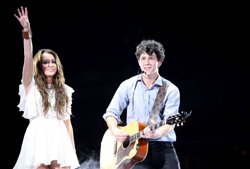 Los músicos Miley Cyrus y Nick Jonas de Jonas Brothers actúan en el New Cowboys Stadium el 20 de junio de 2009 en Dallas, Texas.