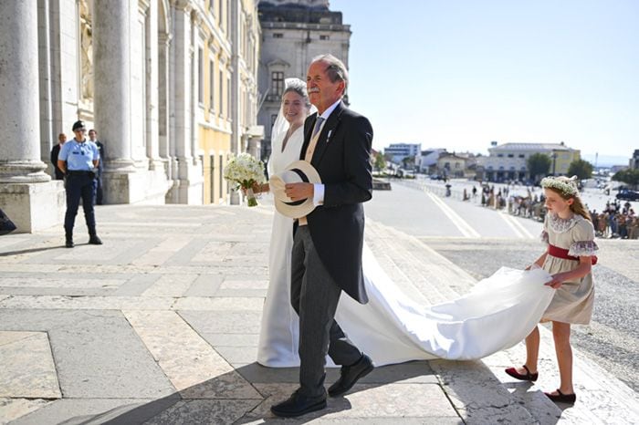 La dama de honor lleva la cola del vestido de la novia