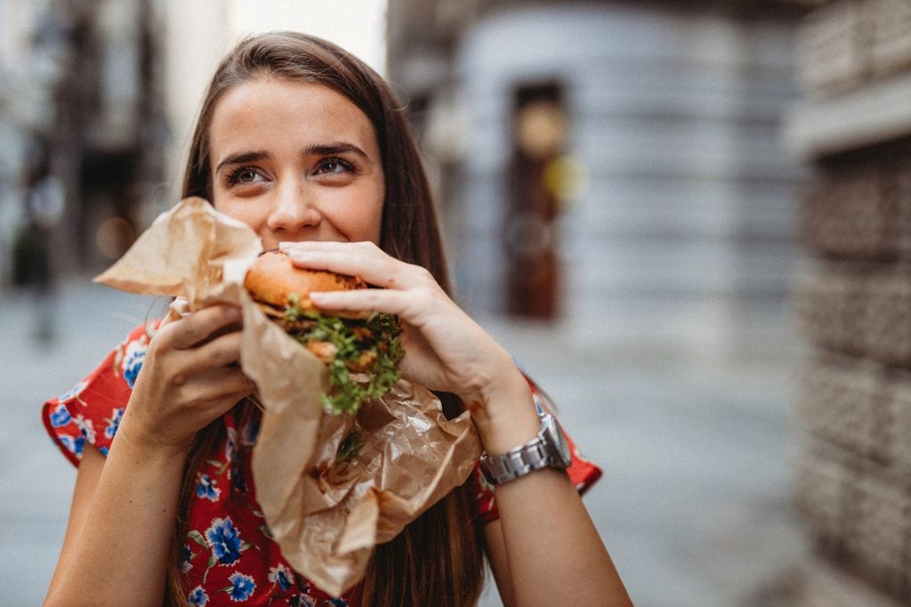 mujer comiendo una hamburguesa en la calle