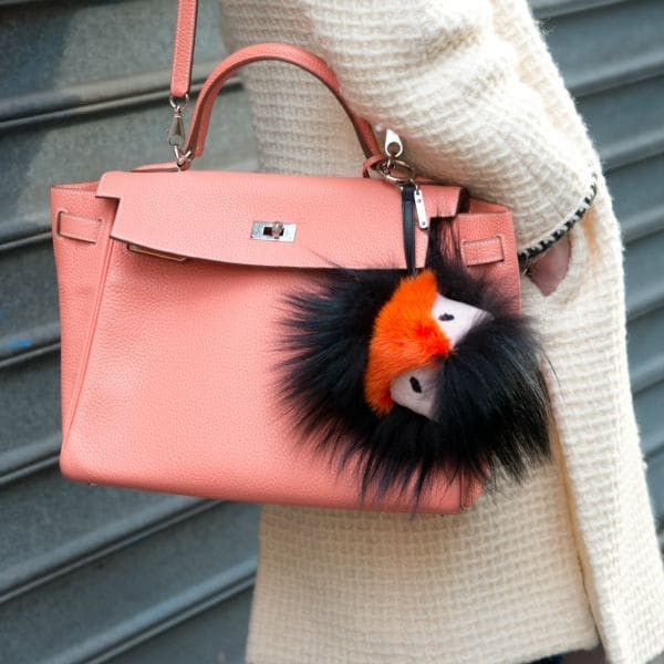 Streetstyler a las puertas del desfile de Chanel, en París, en marzo de 2014, con chaqueta de Chanel jacket y bolso de Hermes en color rosa con pom pom de Fendi.
