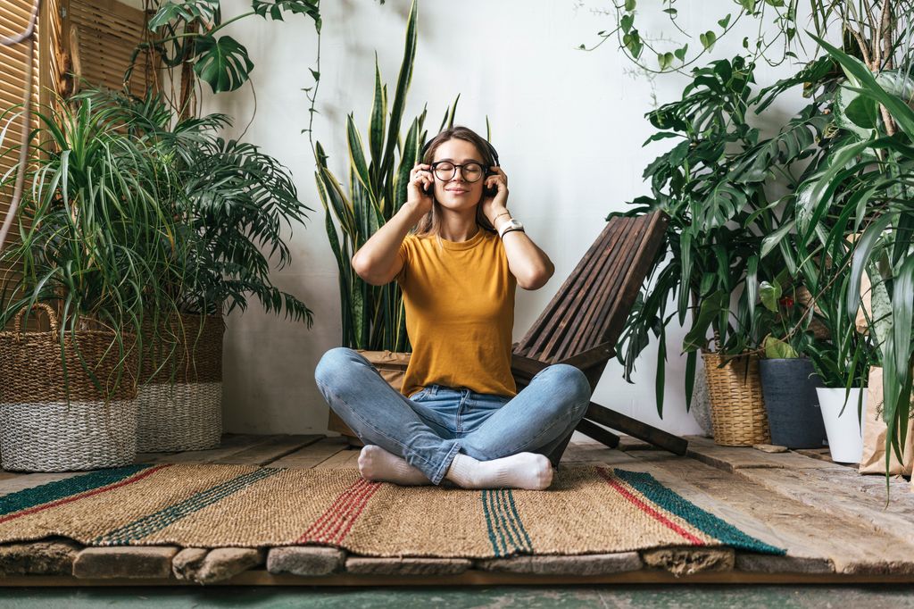 mujer relajada, sentada en el suelo escuchando música con unos auriculares